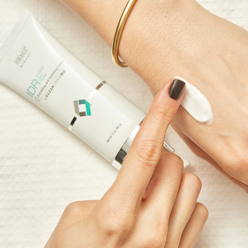 An image of a woman's hand apply SUZANOBAGIMD Intensive Daily Repair lotion. 